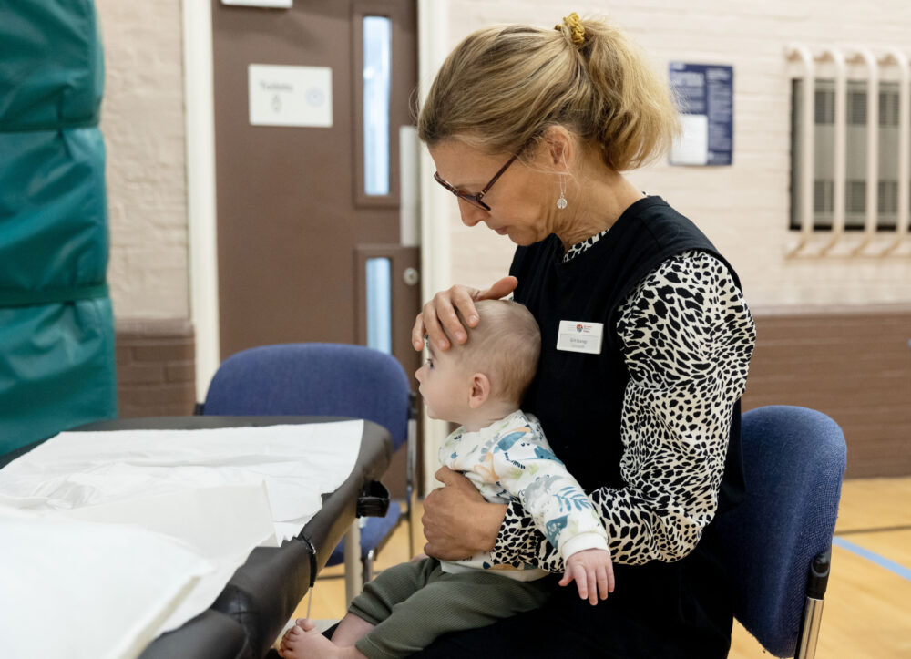 A woman sitting down with a baby on her lap