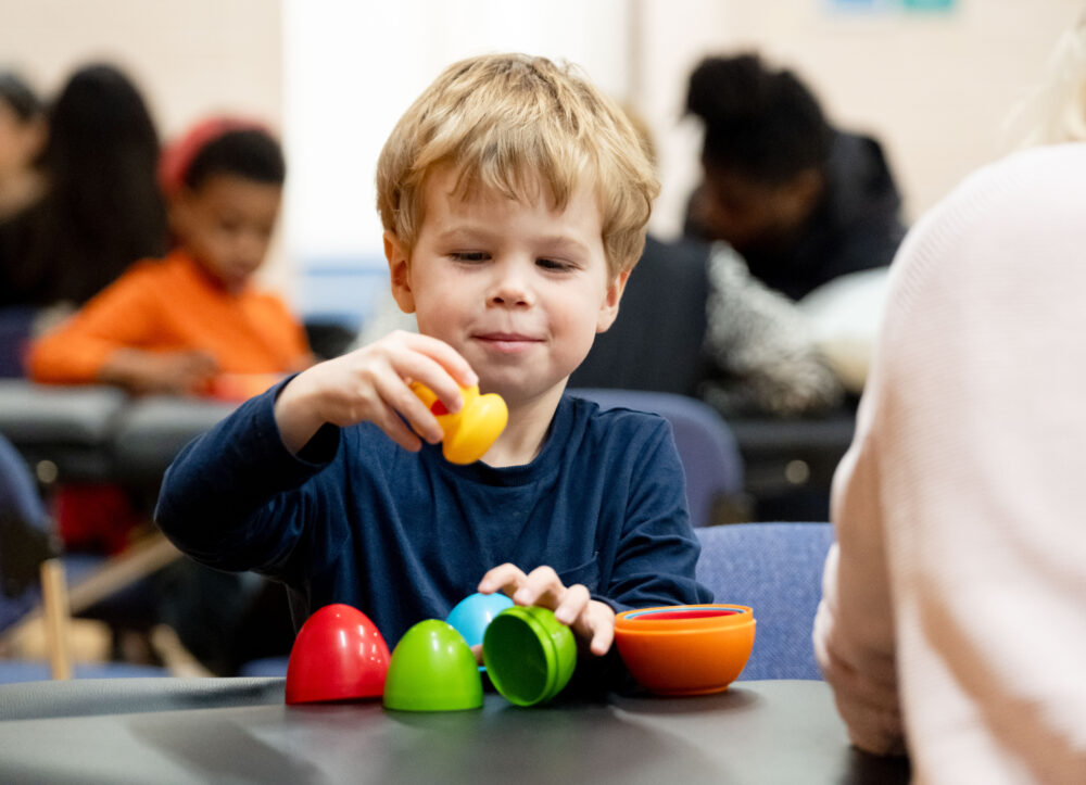A child playing with brightly coloured a nesting egg toy